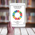 Hand holding an iPad displaying the book cover of "The Trillion Dollar Shift" by Marga Hoek