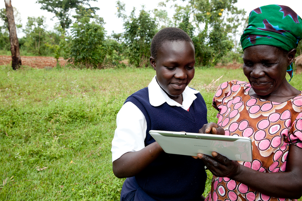 An African woman and school-age girl smiling and using a tablet