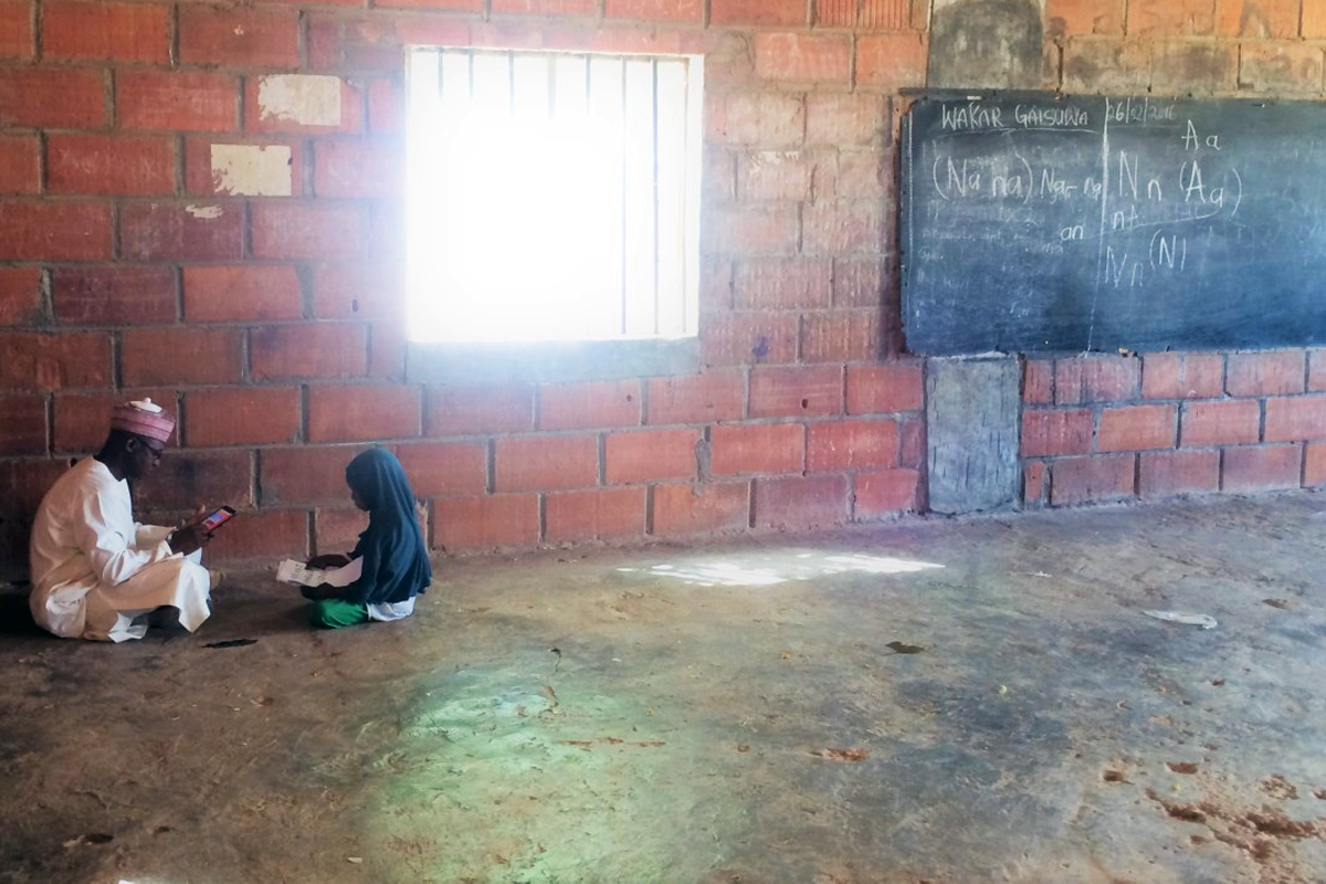 School Support Officer conducting a pupil assessment in an empty classroom in Northern Nigeria