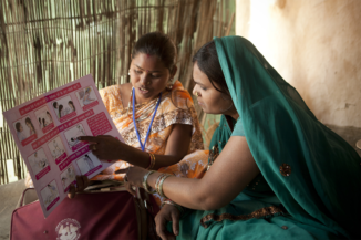 Two Indian women examining a family planning flowchart; one teaching the other