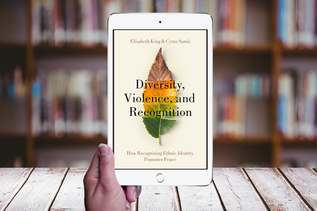 Hand holding a tablet displaying the cover of "Diversity, Violence and Recognition" book by King and Samii