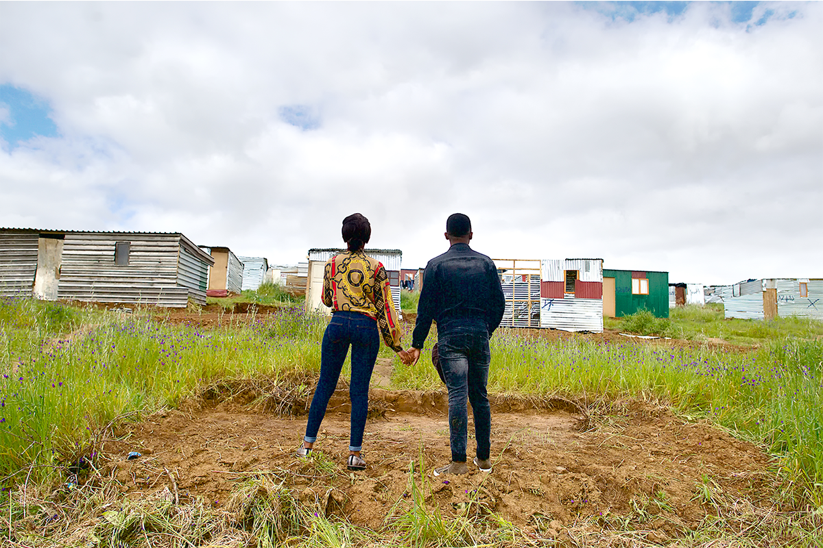 An African heterosexual couple standing on a plot of land in a new development of a township, Cape Town, South Africa (Stock photo)