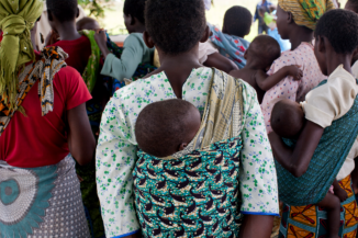 A view from behind of a group of African women with infants on their backs