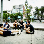 Friends sitting together talking after pick up soccer game in urban park