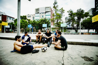 Friends sitting together talking after pick up soccer game in urban park